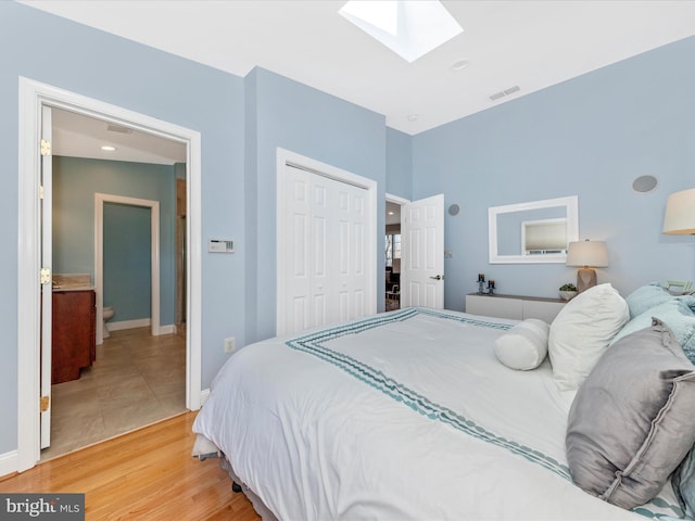 bedroom with visible vents, a closet, a skylight, light wood finished floors, and baseboards