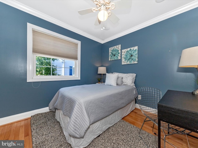 bedroom featuring a ceiling fan, crown molding, baseboards, and wood finished floors