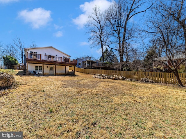 rear view of property with a deck, fence, and a lawn