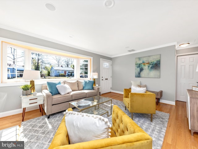 living room featuring visible vents, baseboards, wood finished floors, and crown molding