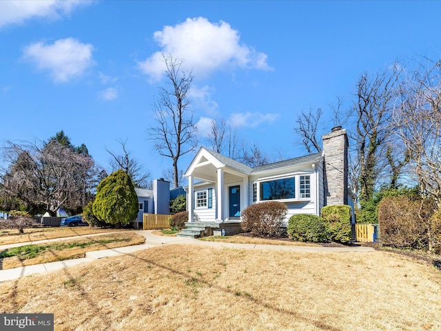 bungalow-style home featuring a chimney, a front yard, and fence