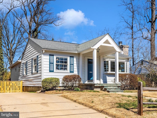 bungalow-style house featuring a chimney and a shingled roof