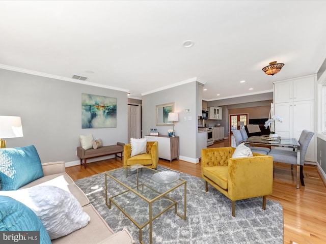 living room featuring ornamental molding, visible vents, light wood-type flooring, and baseboards