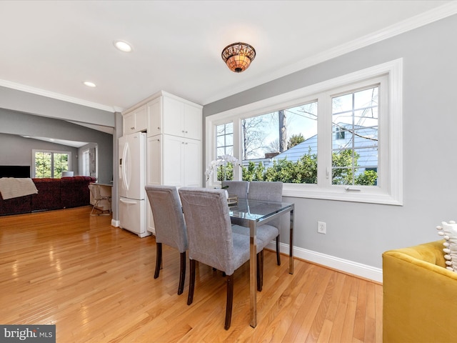 dining space featuring plenty of natural light, light wood-style flooring, and crown molding