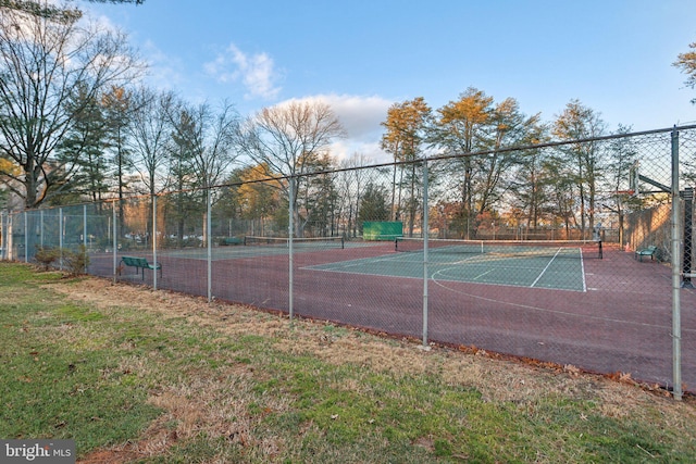 view of tennis court featuring community basketball court and fence