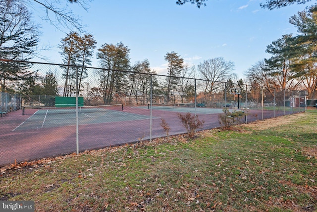 view of sport court with fence and a lawn