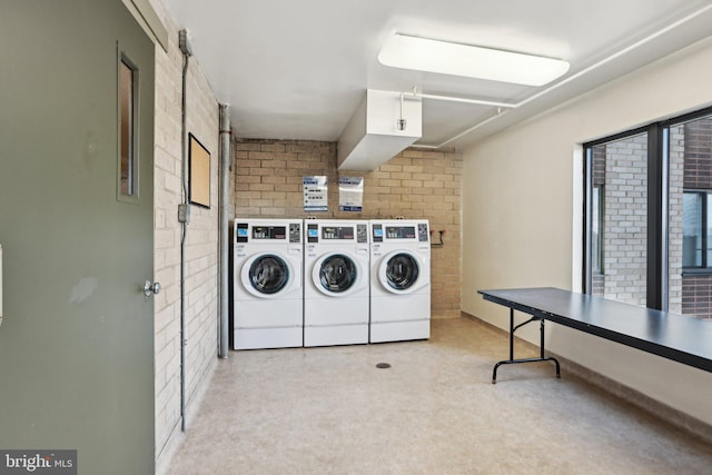 common laundry area featuring washer and clothes dryer and brick wall