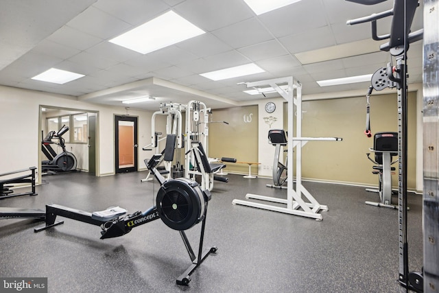 gym with a paneled ceiling and baseboards