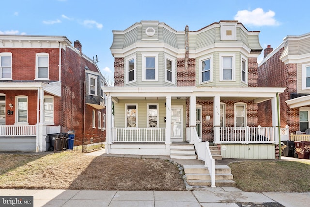 multi unit property featuring covered porch and brick siding