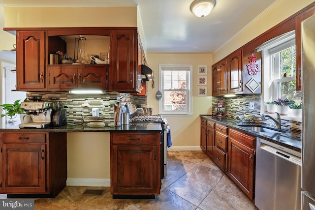 kitchen with dark stone countertops, visible vents, a sink, extractor fan, and appliances with stainless steel finishes