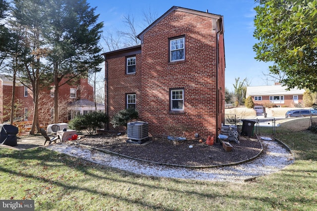 view of home's exterior with central air condition unit, brick siding, a yard, and fence