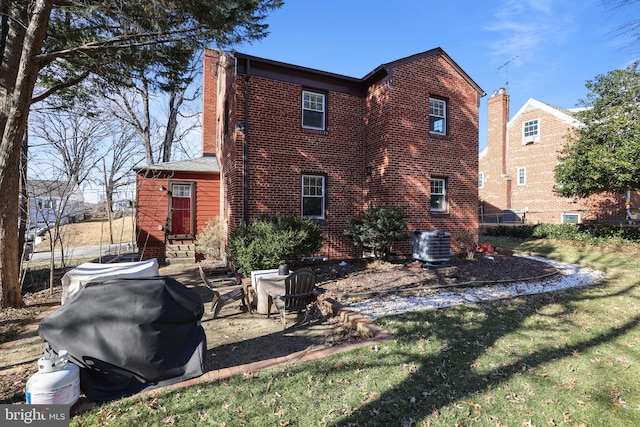 back of property featuring a patio, central air condition unit, a lawn, and brick siding