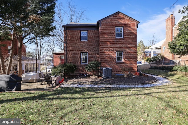 back of property with fence, cooling unit, a lawn, and brick siding