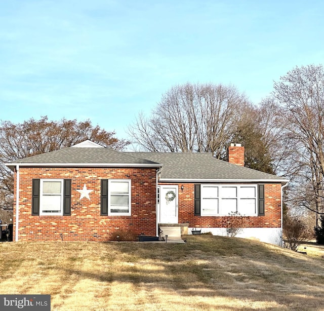 ranch-style house featuring a front yard, brick siding, and a chimney