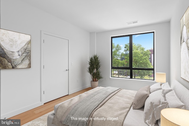 bedroom featuring wood finished floors, visible vents, and baseboards