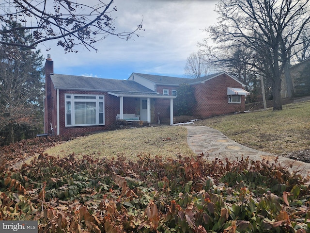 single story home with a chimney, a front lawn, and brick siding