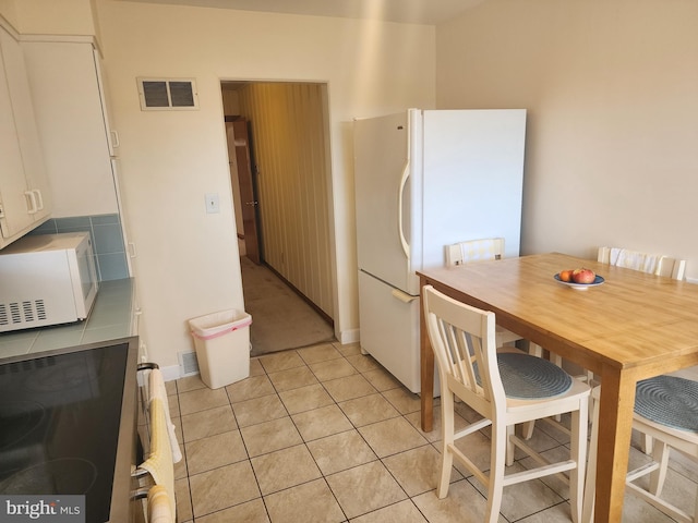 kitchen featuring white appliances, white cabinetry, light tile patterned floors, and visible vents