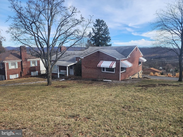 view of side of home featuring brick siding, a lawn, and a chimney