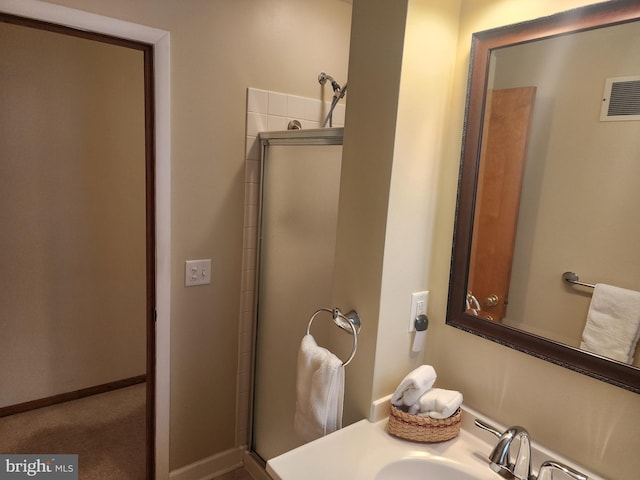 bathroom featuring a stall shower, a sink, visible vents, and baseboards