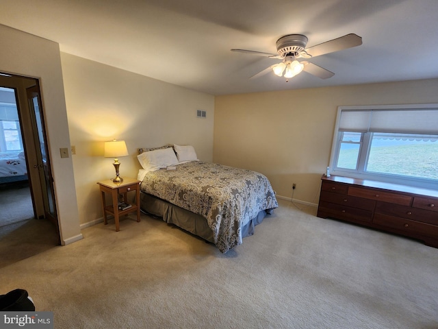 bedroom featuring light carpet, visible vents, baseboards, and ceiling fan