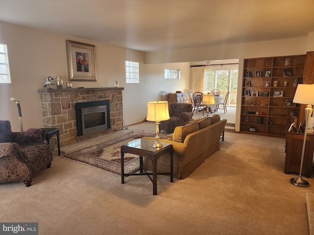 living area with carpet floors and a stone fireplace