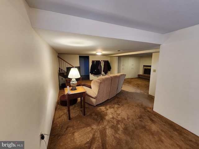 living area featuring a fireplace with raised hearth, carpet floors, stairway, and visible vents