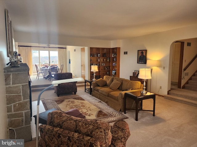 carpeted living area with arched walkways and stairs