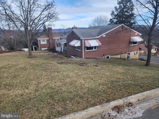 view of property exterior featuring brick siding, a yard, and a chimney