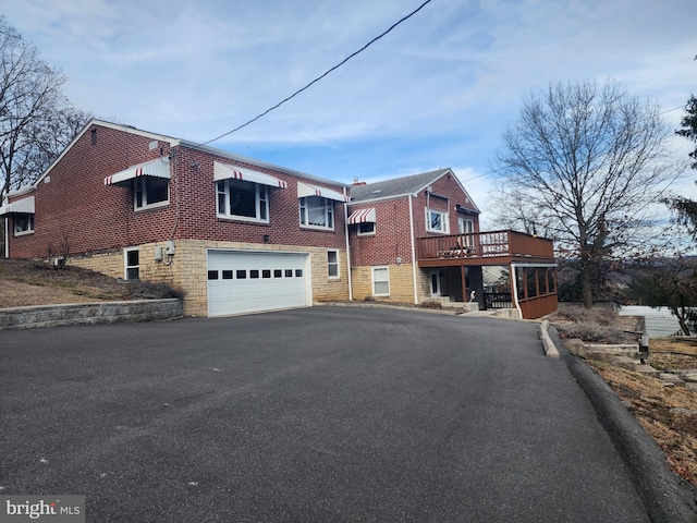 townhome / multi-family property with a garage, aphalt driveway, and brick siding