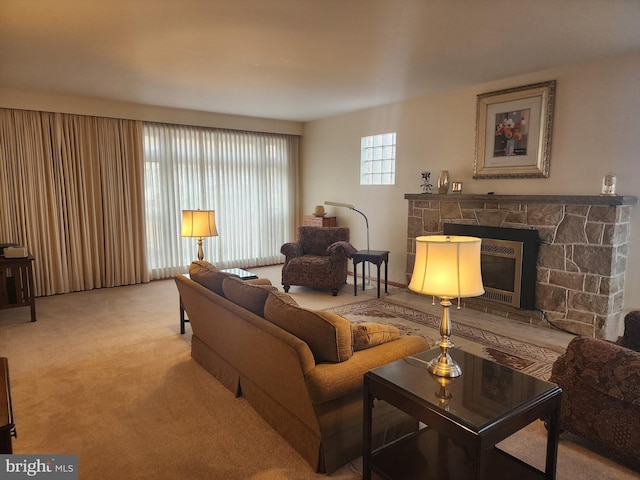 living area featuring carpet and a stone fireplace