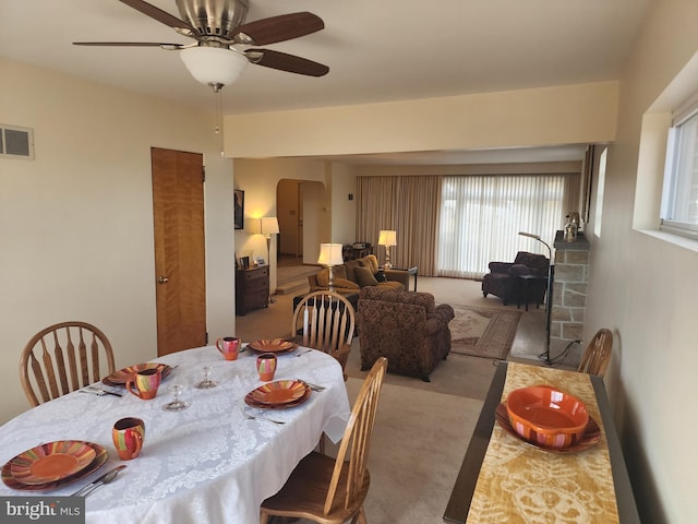 dining space with a ceiling fan, visible vents, arched walkways, and carpet flooring