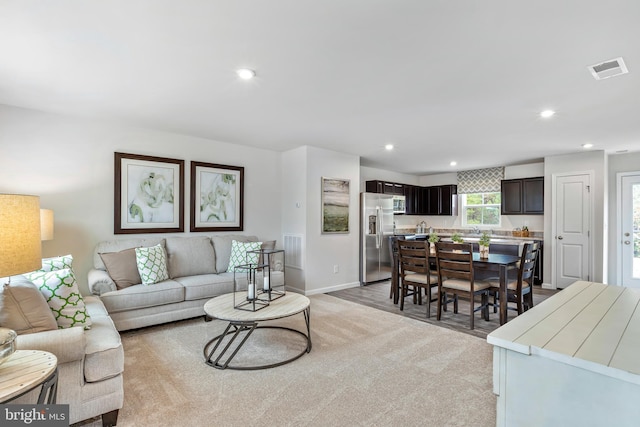 living area with light colored carpet, visible vents, and recessed lighting