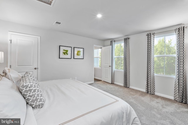 bedroom featuring carpet floors, visible vents, multiple windows, and baseboards