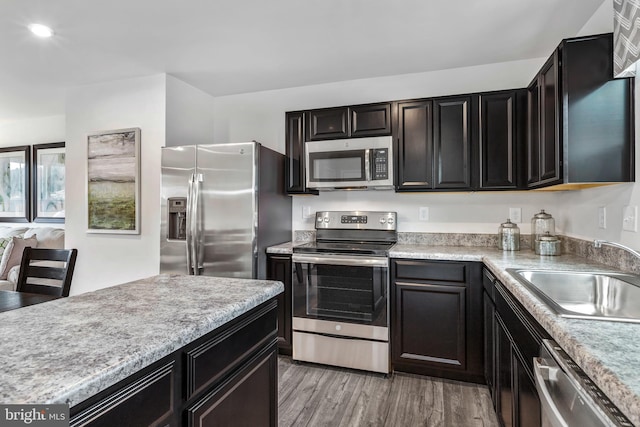 kitchen with stainless steel appliances, light countertops, light wood-style floors, a sink, and recessed lighting