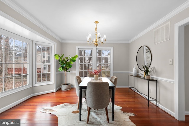 dining space featuring a chandelier, visible vents, crown molding, and hardwood / wood-style flooring