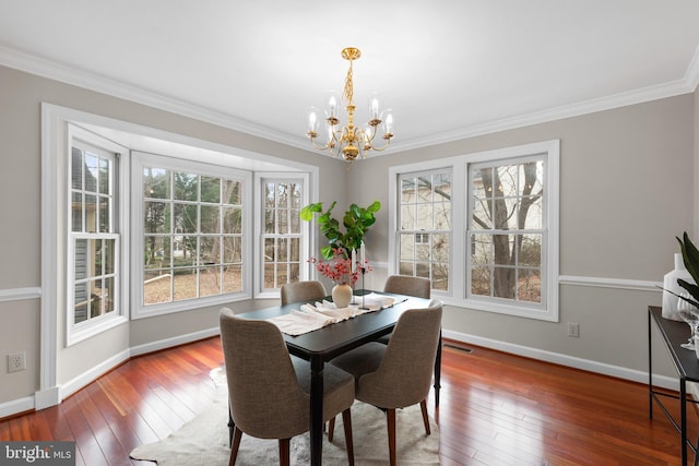 dining room with baseboards, a notable chandelier, hardwood / wood-style floors, and ornamental molding