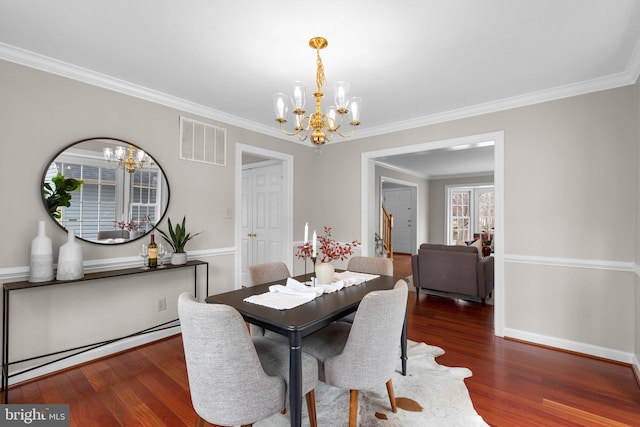 dining room featuring wood finished floors, baseboards, visible vents, ornamental molding, and a notable chandelier