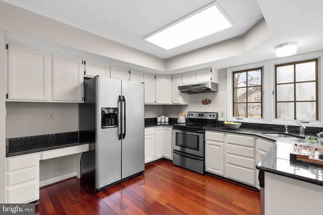 kitchen with under cabinet range hood, dark wood-style flooring, appliances with stainless steel finishes, white cabinets, and a sink