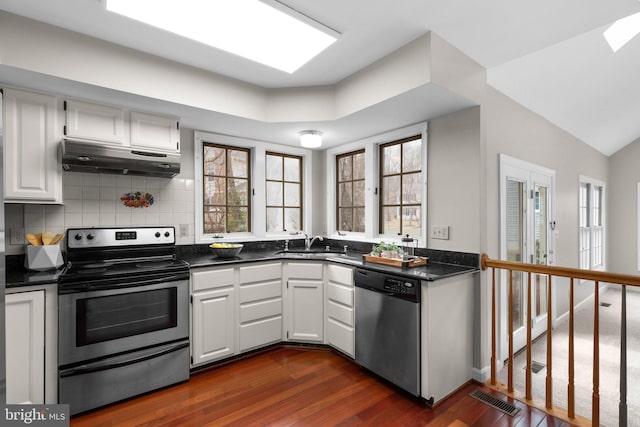 kitchen featuring visible vents, under cabinet range hood, a sink, dark countertops, and appliances with stainless steel finishes