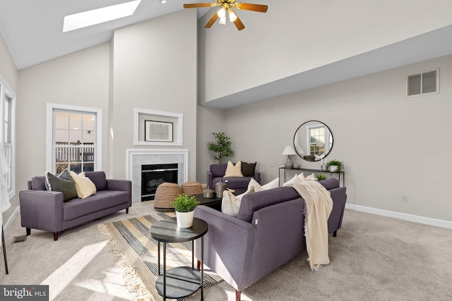 living room featuring visible vents, light carpet, a tiled fireplace, a skylight, and baseboards