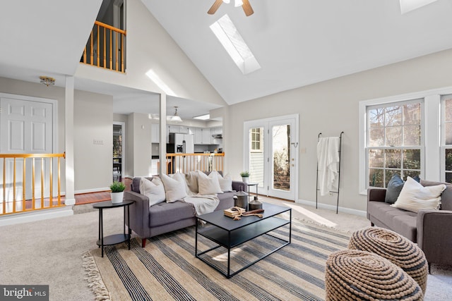 living room featuring baseboards, a healthy amount of sunlight, a skylight, and a ceiling fan