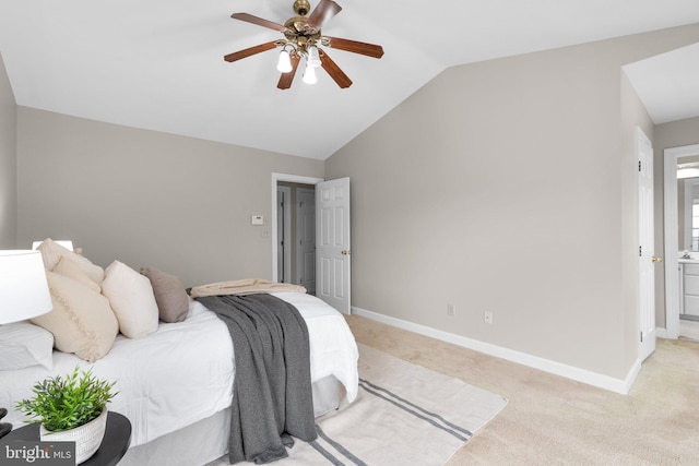 bedroom featuring a ceiling fan, baseboards, lofted ceiling, ensuite bath, and light colored carpet