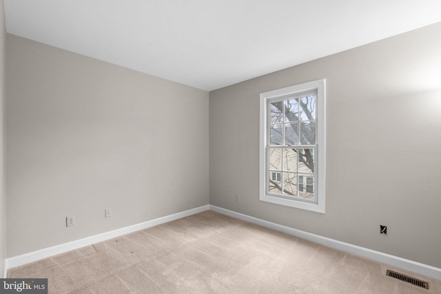 empty room featuring visible vents, light colored carpet, and baseboards