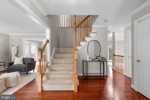 stairs featuring baseboards, hardwood / wood-style floors, and crown molding