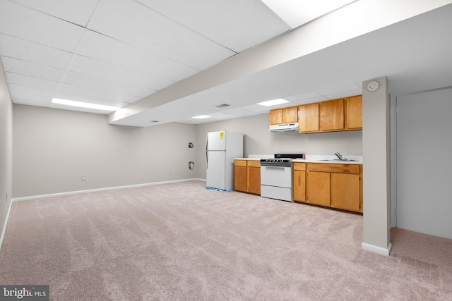 kitchen featuring light colored carpet, light countertops, white appliances, a paneled ceiling, and a sink