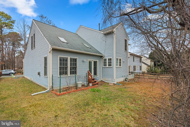 back of property featuring a lawn, entry steps, a shingled roof, and fence