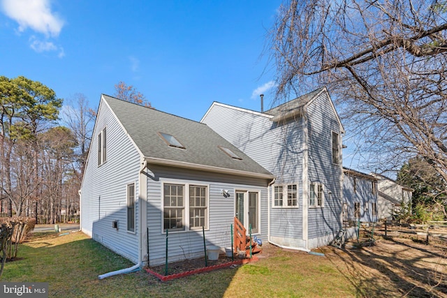 back of house featuring a lawn and roof with shingles