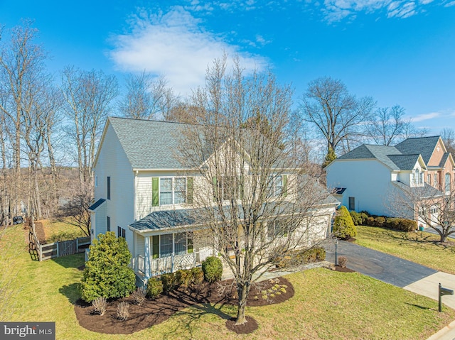 view of front of house with fence, aphalt driveway, roof with shingles, a front yard, and covered porch