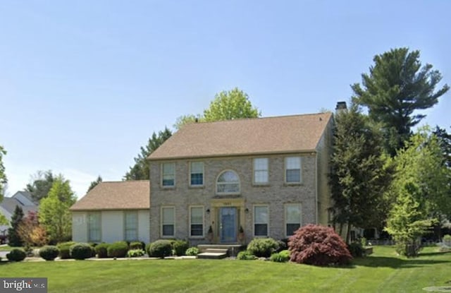 colonial home with a chimney and a front yard