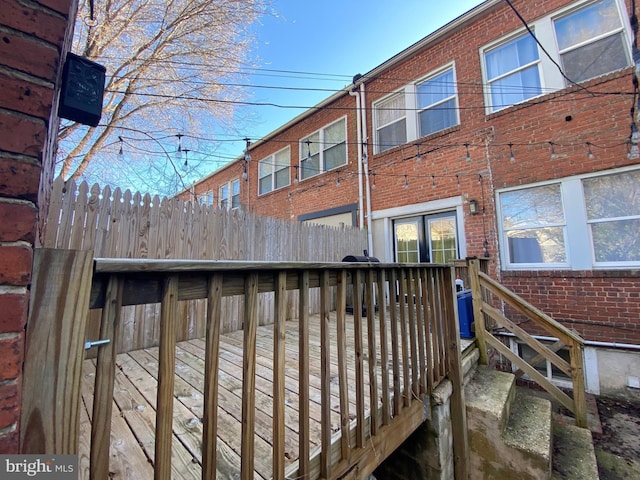 back of house featuring a wooden deck, fence, and brick siding